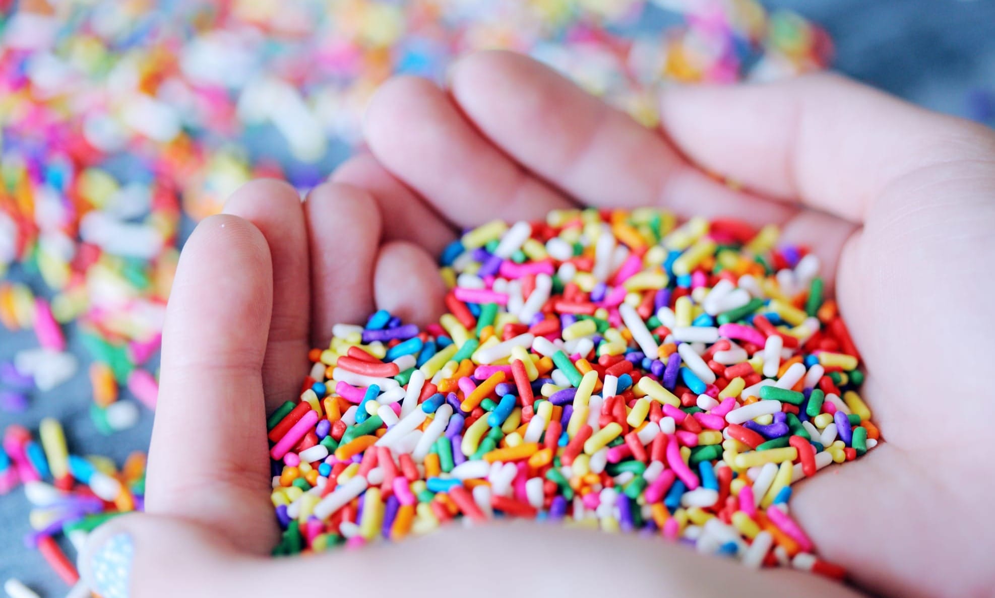 Hands holding a pile of rainbow sprinkles