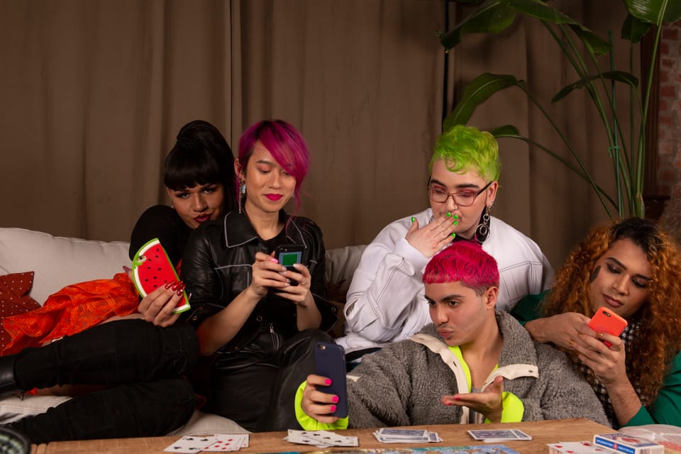 A group of friends of varying genders taking selfies.